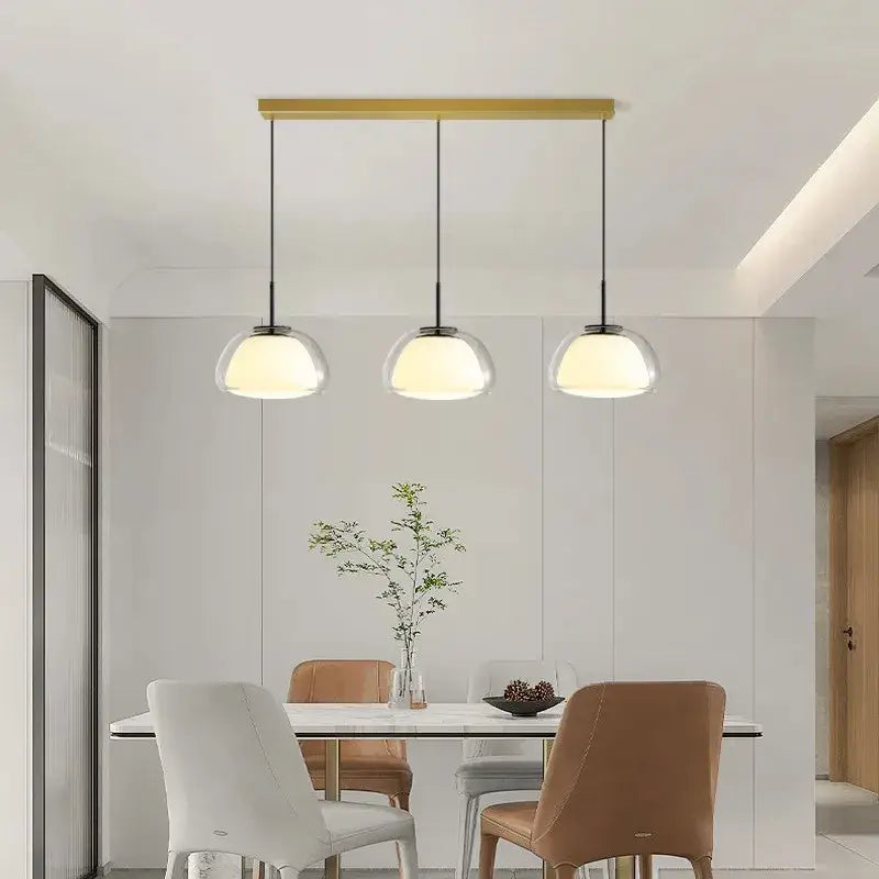 Minimalist clear glass jelly pendant lamp with three spherical shades and gold-toned bar for living room lighting