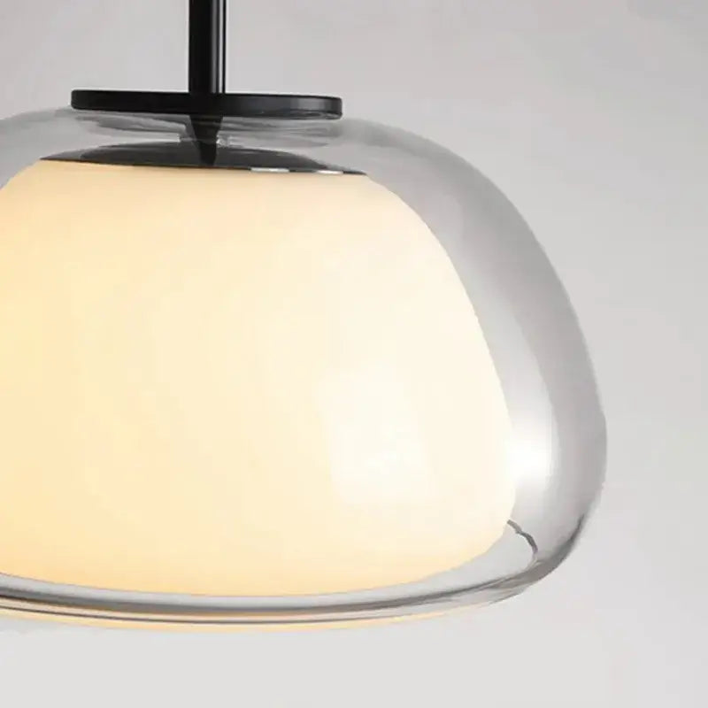 Minimalist clear glass jelly pendant lamp with warm glowing shade and black metal hardware for living room lighting