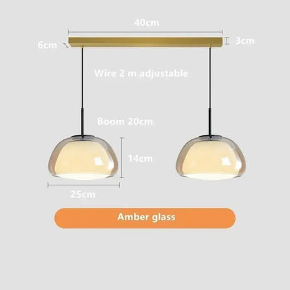 A pair of modern minimalist jelly pendant lamps with amber glass domes and brass horizontal bar for living room
