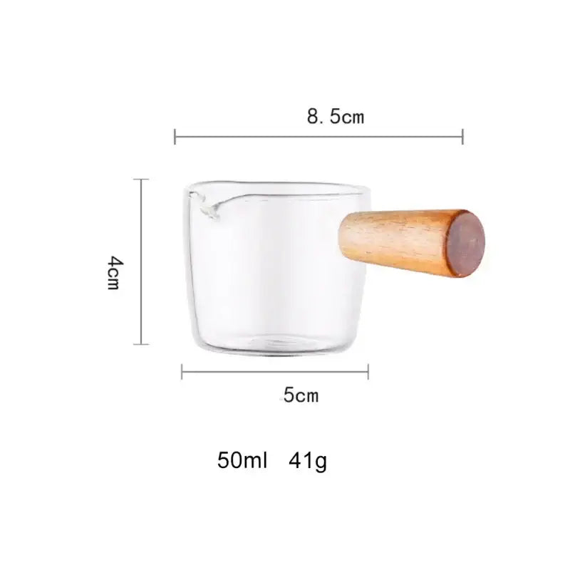 Minimalist clear glass sauce dish with wooden handle in clear glass and light brown wood, 50ml capacity measuring cup