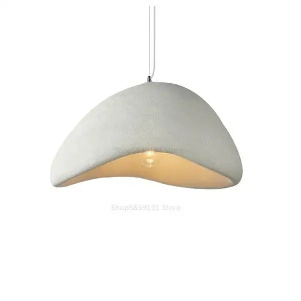 A modern off-white concrete decorbites cobblestone pendant light with a smooth dome and exposed warm bulb for dining room