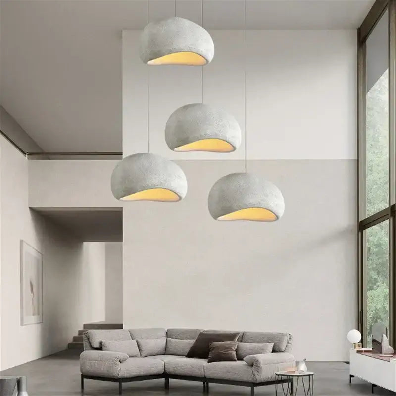 Four minimalist concrete cobblestone pendant lights with matte gray finish and warm yellow glow for dining room decorbites pendant lights