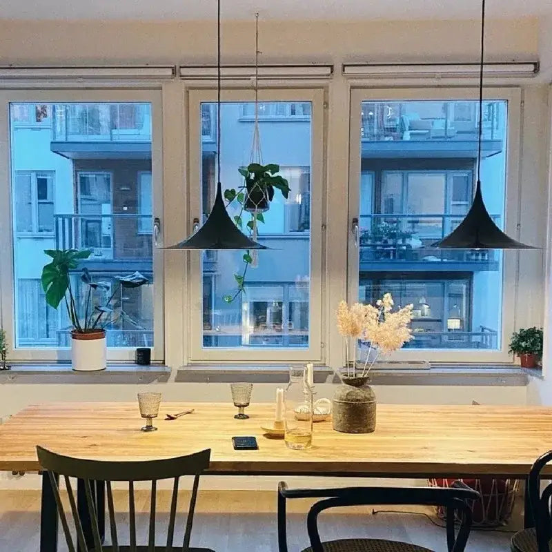 Black conical pendant lights hanging above a wooden dining table featuring minimalist copper horn chandelier pendant decorbites horn chandelier