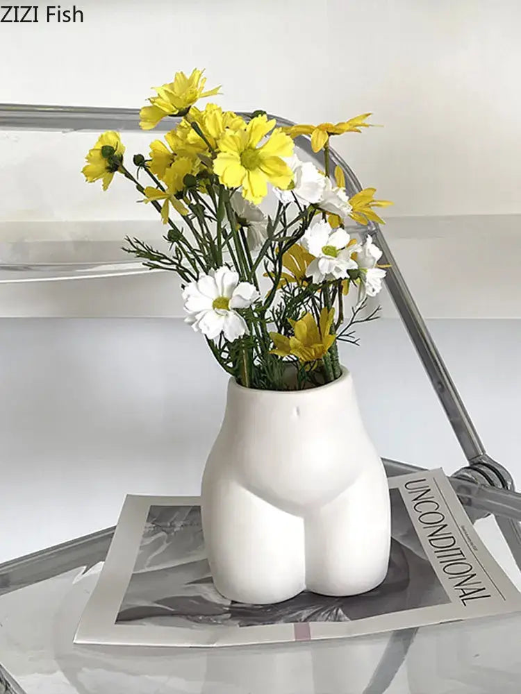Minimalist cream abstract human ceramic body vase shaped like buttocks holding yellow and white flowers for decorbites decor