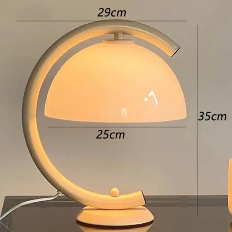 Minimalist cream bauhous mushroom table lamp with sleek metallic base and warm amber glass dome for bedroom use