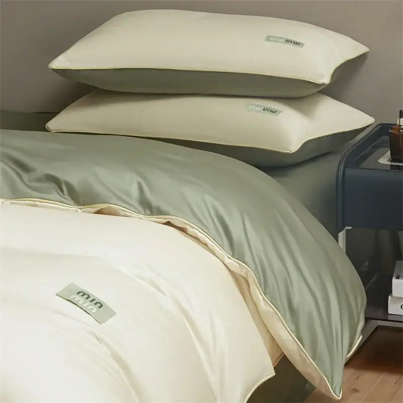 Cream-colored satin pillowcases with subtle gray branding tags in minimalist cream and green egyptian cotton solid bedding set