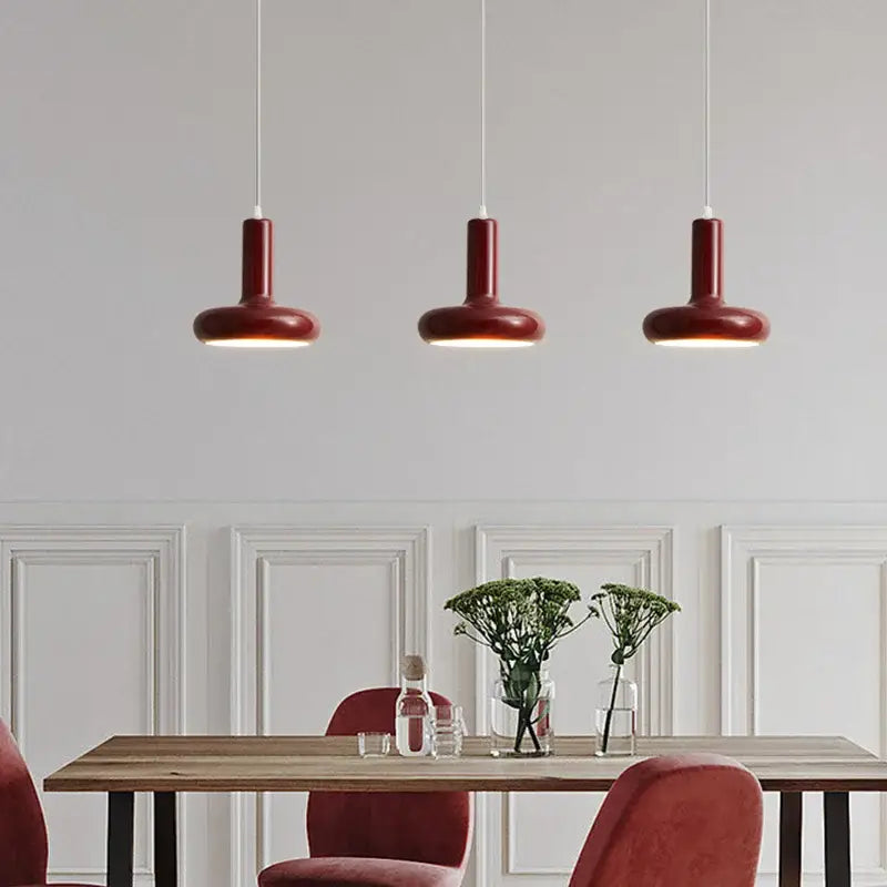Three burgundy cylindrical pendant lights complement minimalist cream white ceramic pendant light decorbites disc shaped design