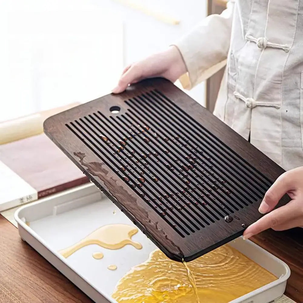 Minimalist dark brown and black bamboo tea tray with parallel slits and central hole for draining water during tea preparation