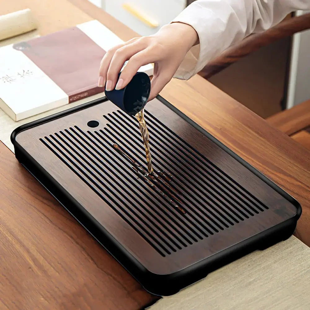 Minimalist dark brown and black bamboo tea tray with parallel slotted drainage grooves for dining room storage