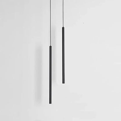 Two sleek black cylindrical decorbites black slim led pendant lamps hang vertically against a plain white background