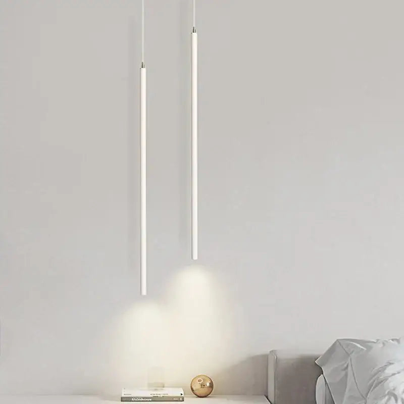 Two minimalist white cylindrical led pendant lamps hang casting soft glow in a decorbites black slim dining room light setting