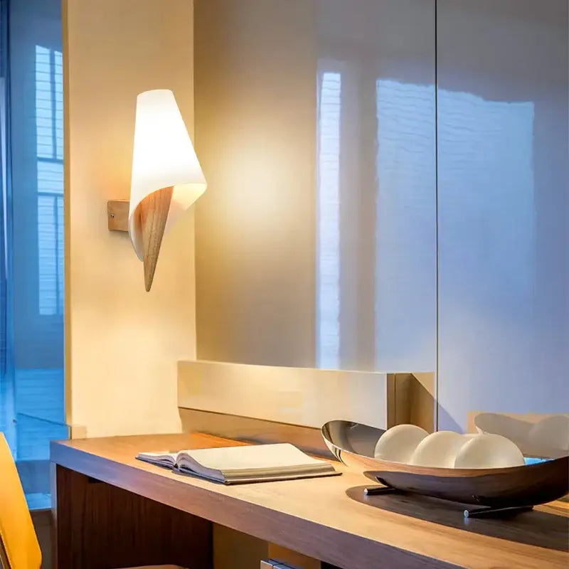 Modern white ceramic wall sconce with a sleek, tapered design and wooden accent.