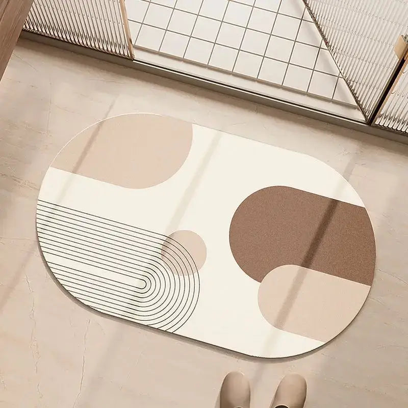 A modern oval minimalist geometric diatom ooze bathroom rug in cream and beige with abstract shapes on white background