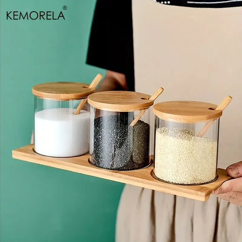 Set of three clear glass spice jars with bamboo lids and wooden spoons for minimalist kitchen organization