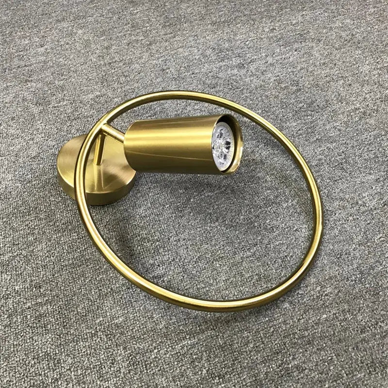 Minimalist gold-toned cylindrical wall light with adjustable angle and circular ring accent for decorbites wall light bedroom sconce