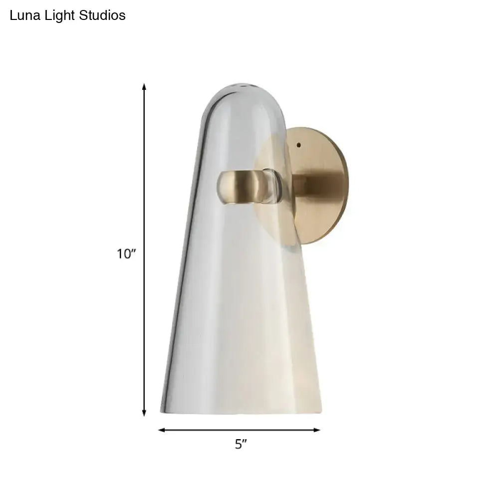 A sleek minimalist gold and clear acrylic wall mount lighting sconce with a translucent glass shade and brushed brass accents