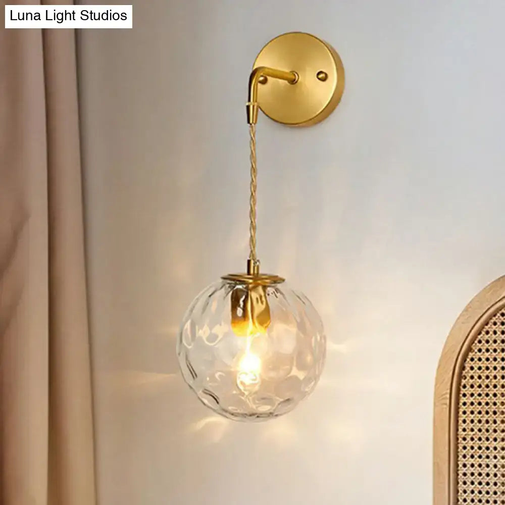 Minimalist gold ball sconce with hammered glass shade textured clear globe and braided cord for bedroom lighting