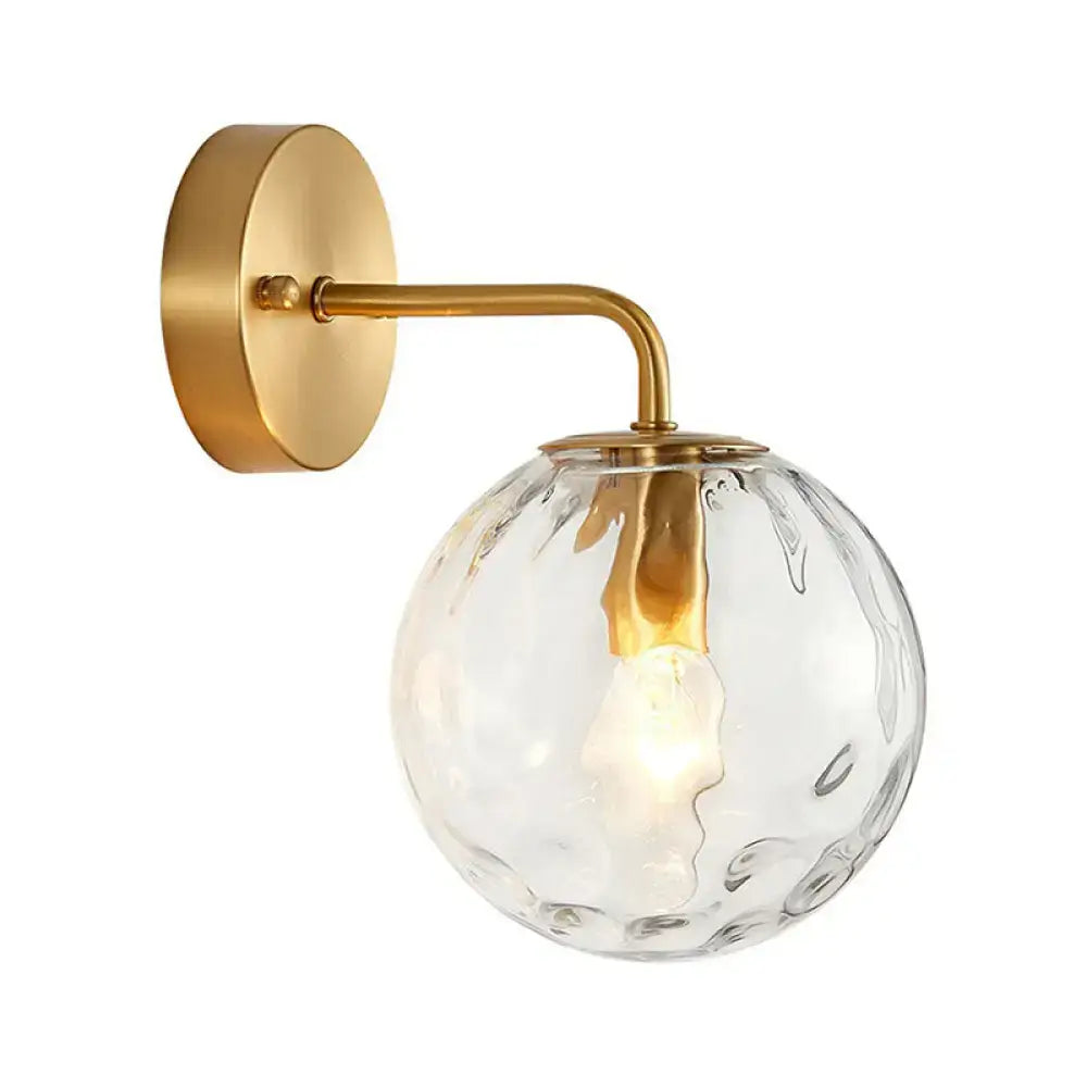 Minimalist gold ball sconce with hammered glass shade and brass hardware featuring a textured clear globe