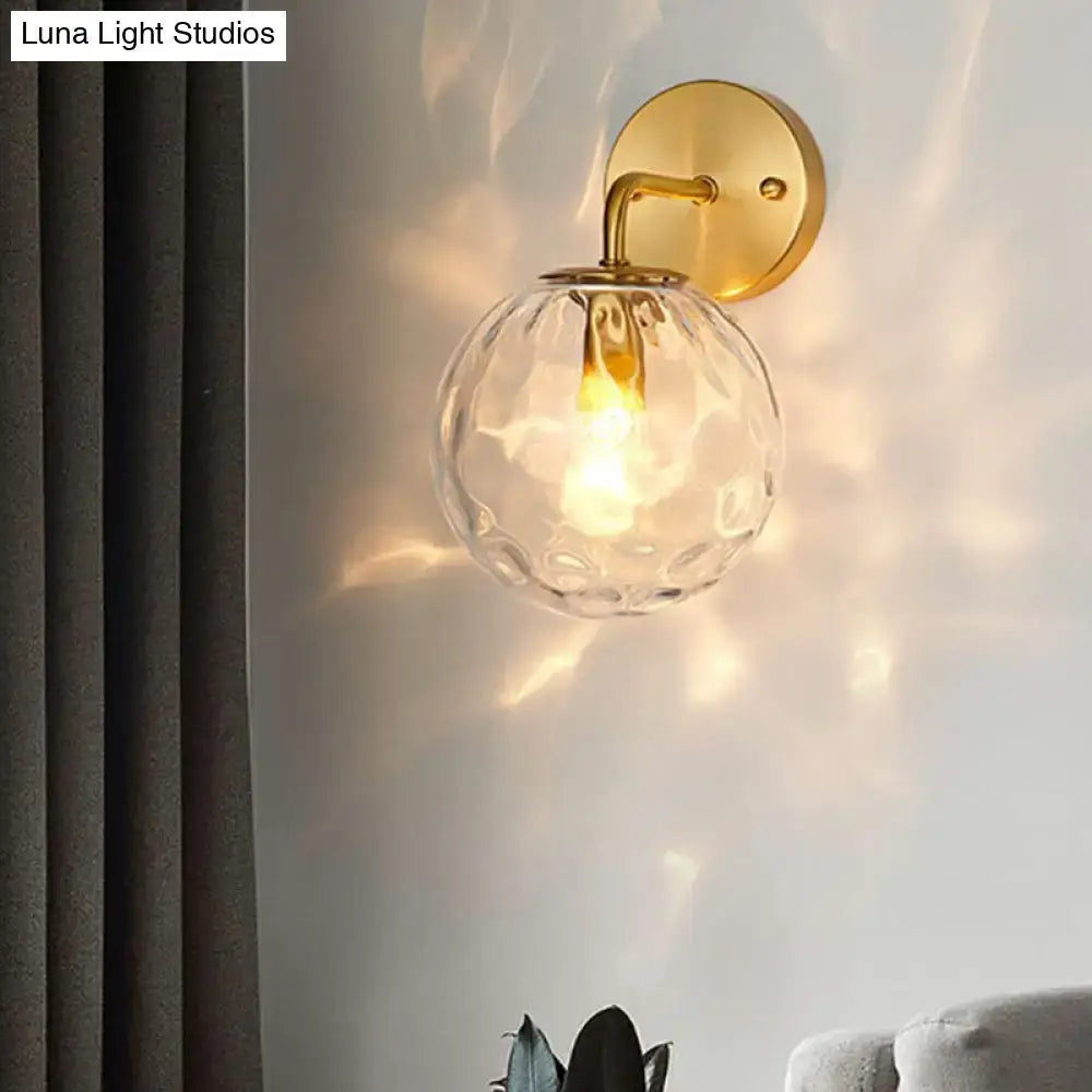Minimalist gold ball sconce with hammered glass shade and textured clear globe ideal for bedroom lighting