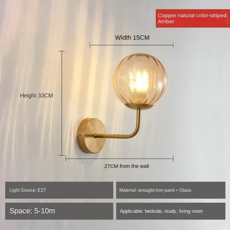 Copper-colored wall lamp with a spherical amber glass ball led shade featuring vertical striations for bedroom decorbites