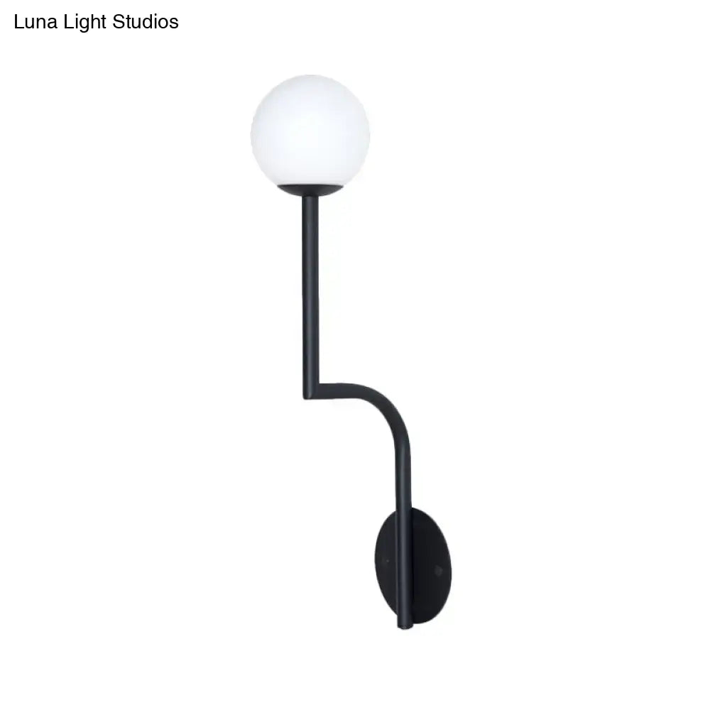 Black metal wall sconce with long curved arm and frosted white opal glass spherical shade for bedroom use