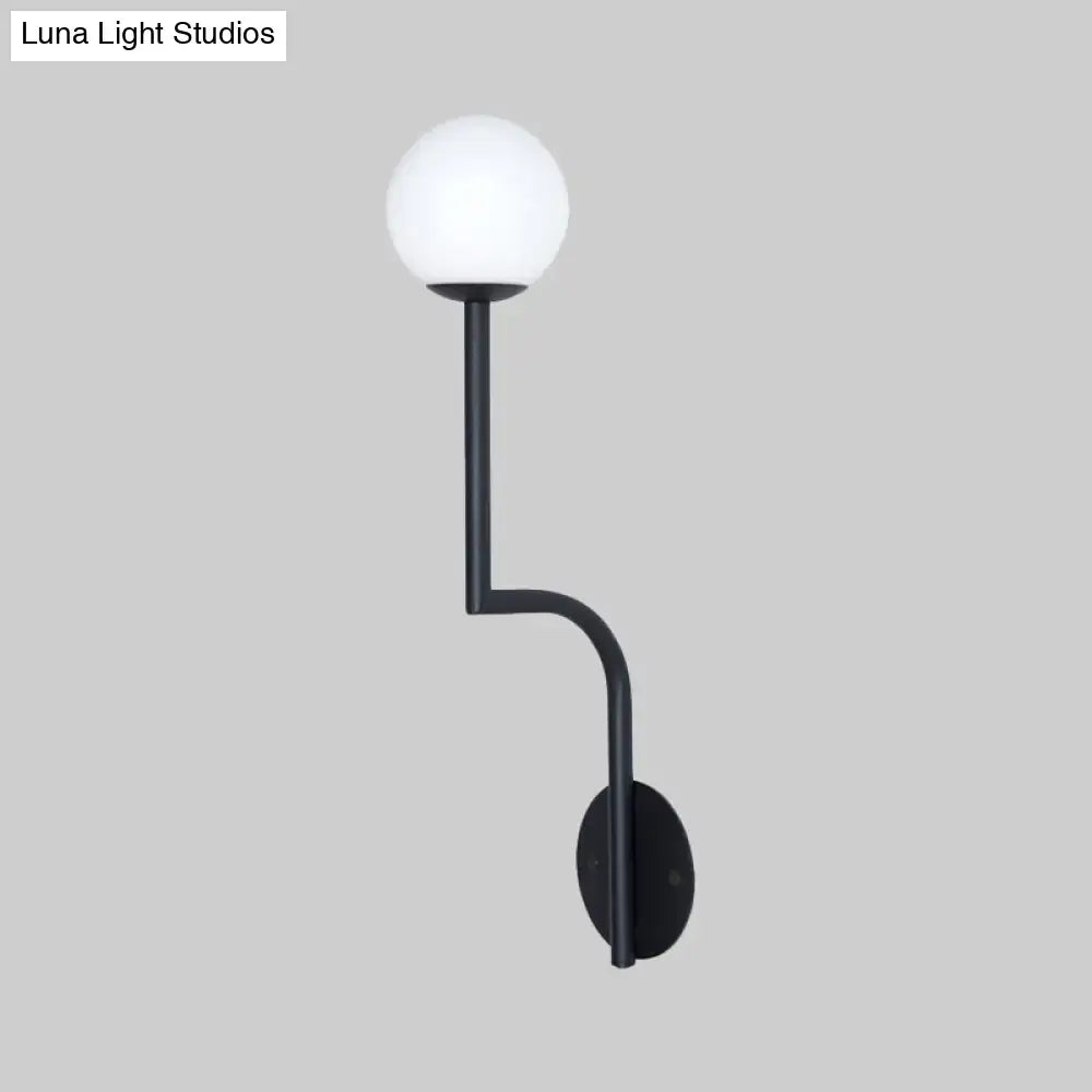 Black modern wall sconce with long curved arm and opal glass spherical frosted globe for minimalist bedroom use