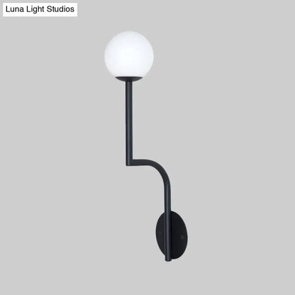 Black modern wall sconce with long curved arm and opal glass spherical frosted globe for minimalist bedroom use