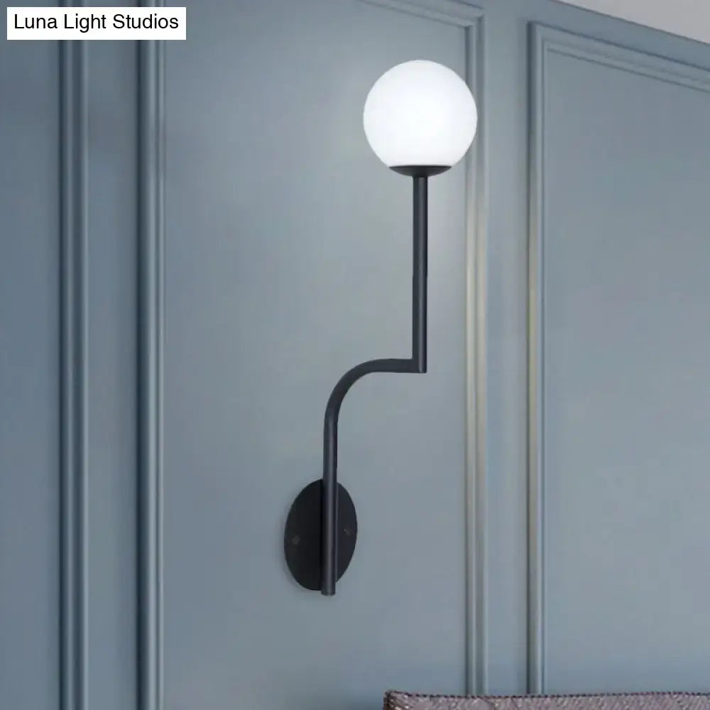 Black metal wall sconce with frosted opal glass globe and long curved arm for minimalist bedroom lighting