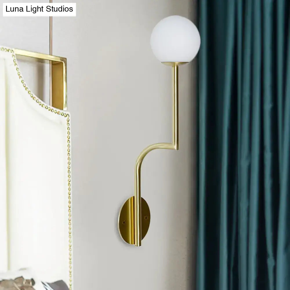 Minimalist gold wall sconce with long curved arm and frosted white opal glass shade for bedroom lighting