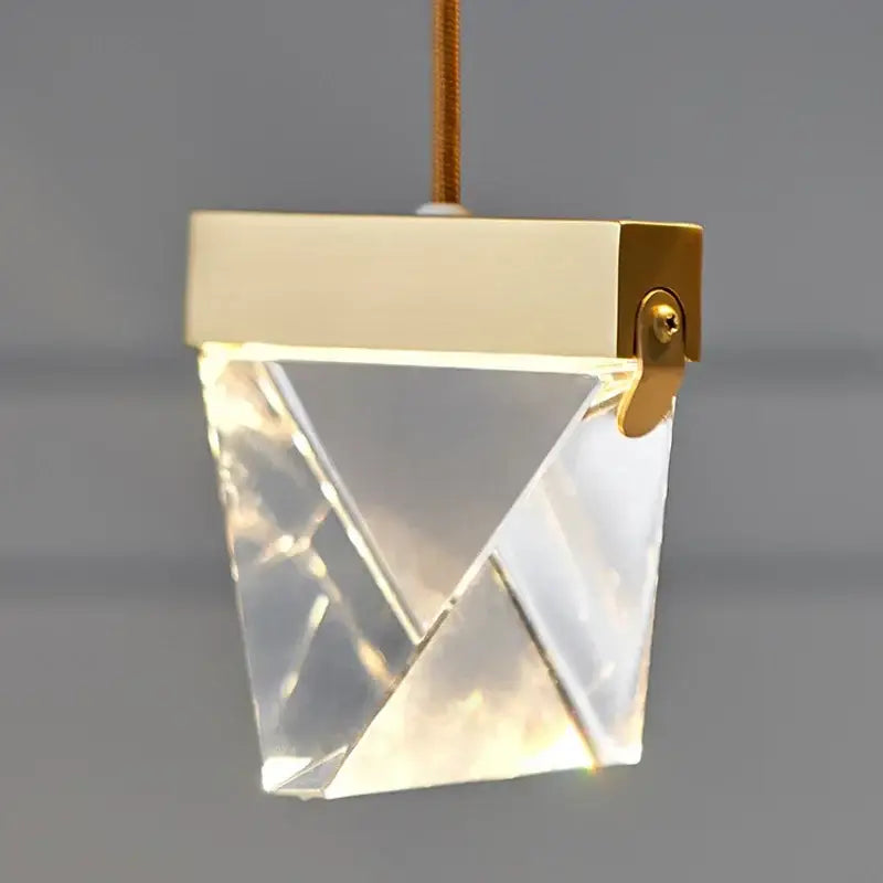 A modern gold-toned decorbites crystal chandelier with faceted crystal body for minimalist dining room lighting
