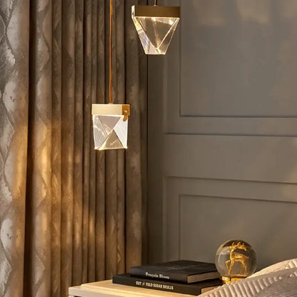 Two minimalist gold decorbites crystal chandelier pendant lights with geometric crystal design hang in a dining room