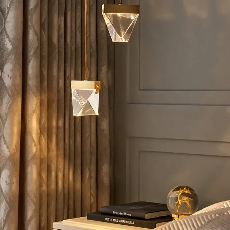 Two minimalist gold decorbites crystal chandelier pendant lights with geometric crystal design hang in a dining room
