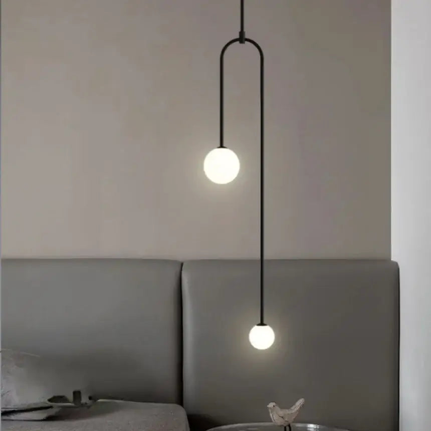 Black minimalist pendant light with double head glass ball frosted bulbs and curved metal arm for bedroom use