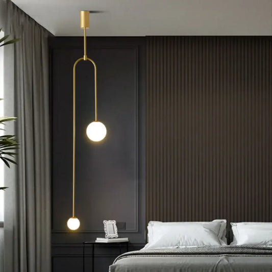 Minimalist gold-toned pendant light with double head glass balls suspended by a curved metal arm for bedroom use