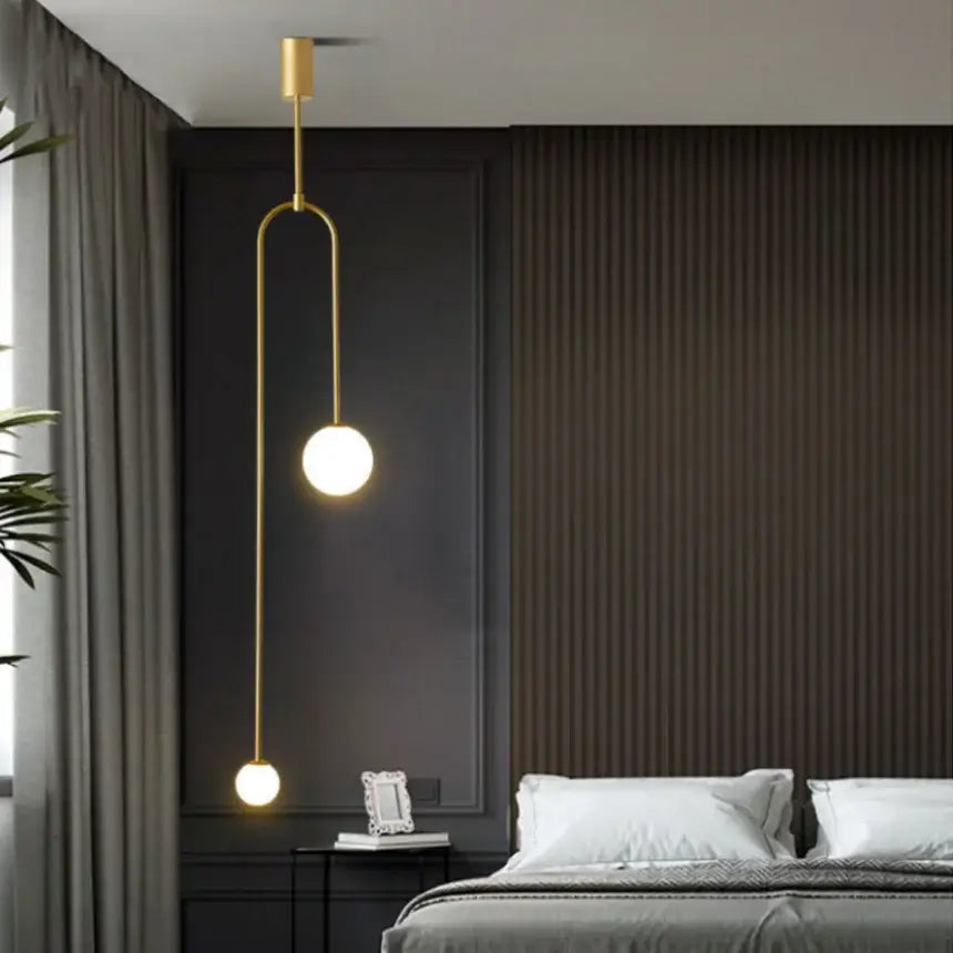 Minimalist gold-toned pendant light with double head glass balls suspended by a curved metal arm for bedroom use