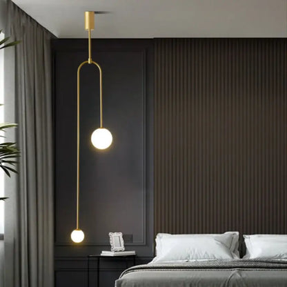 Minimalist gold double head glass ball pendant lights with spherical bulbs and curved metal arm for bedroom lighting
