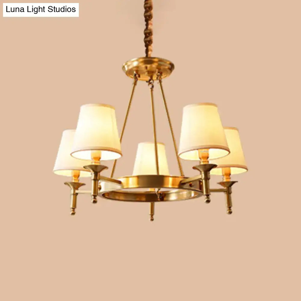 Brass-finished minimalist conical ceiling chandelier with five cream-colored fabric bedroom shades