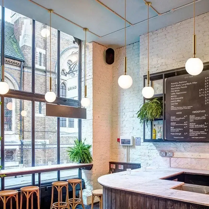 Minimalist gold glass ball led pendant chandelier with decorbites glass ball design in modern café with marble countertop