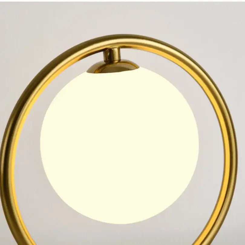 Minimalist gold table lamp with a glowing white glass ball led shade for bedroom decor by decorbites glass ball