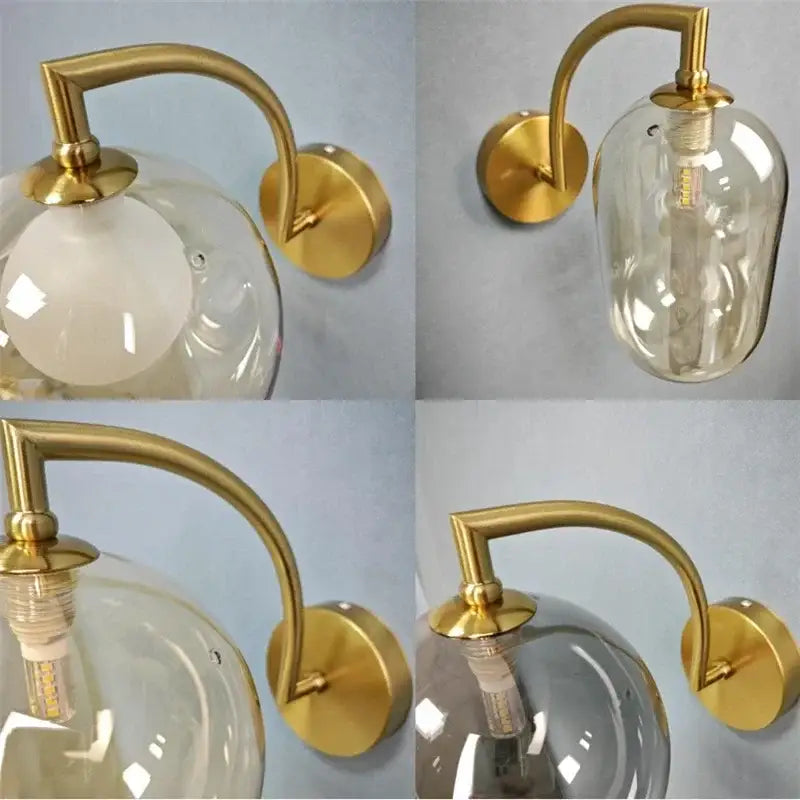 Minimalist gold wall sconce with curved arm and clear glass ball globe housing exposed bulb for bedroom use