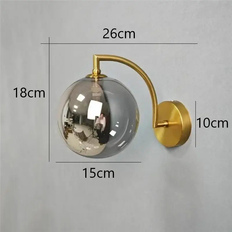 Minimalist gold wall sconce with a reflective smoked glass ball wall lamp ideal for bedroom use