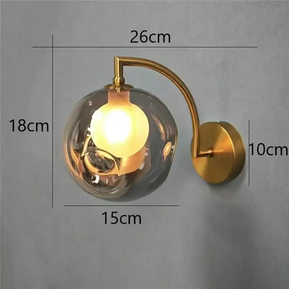 Minimalist gold glass ball wall sconce with a gold-toned wall lamp and smoked glass globe for bedroom lighting
