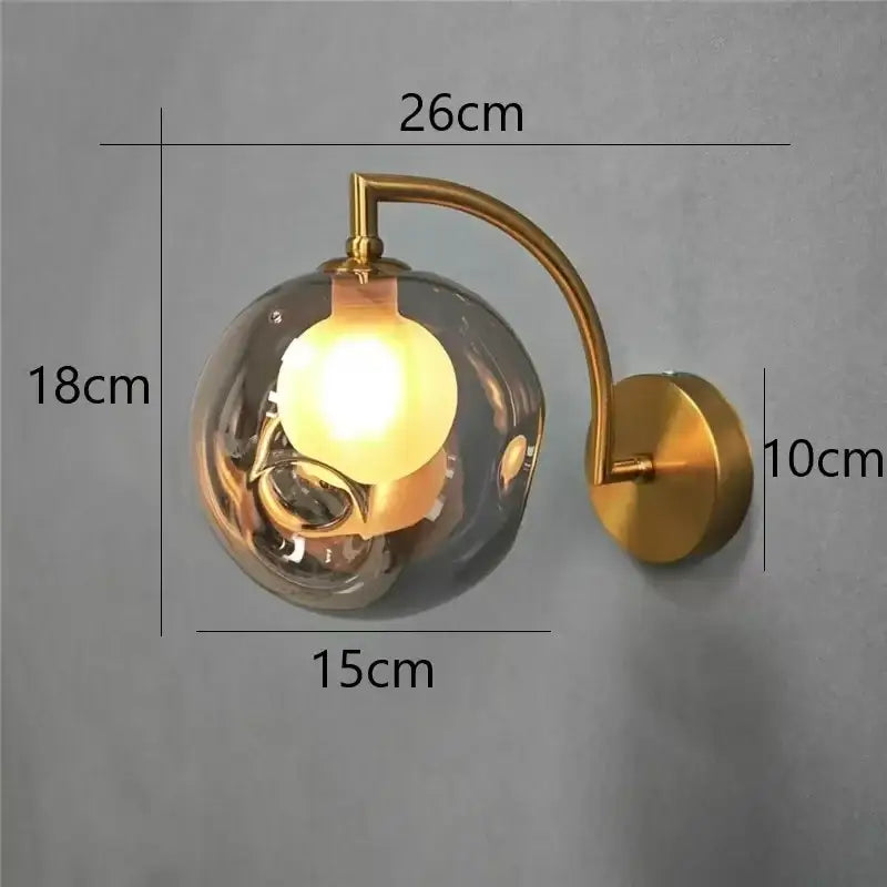 Minimalist gold glass ball wall sconce with a gold-toned wall lamp and smoked glass globe for bedroom lighting
