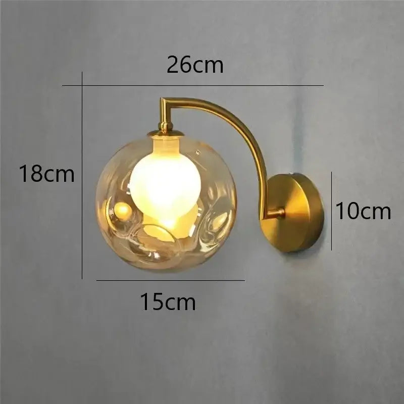 Minimalist wall sconce with a gold-toned frame and textured translucent glass ball wall lamp for bedroom lighting