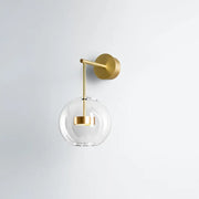 Minimalist gold-toned wall hanging light with clear glass globe and brass hardware for bedroom sconce lighting