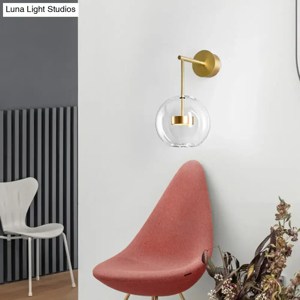Minimalist gold-toned wall hanging light with clear glass globe shade for bedroom wall sconce lighting
