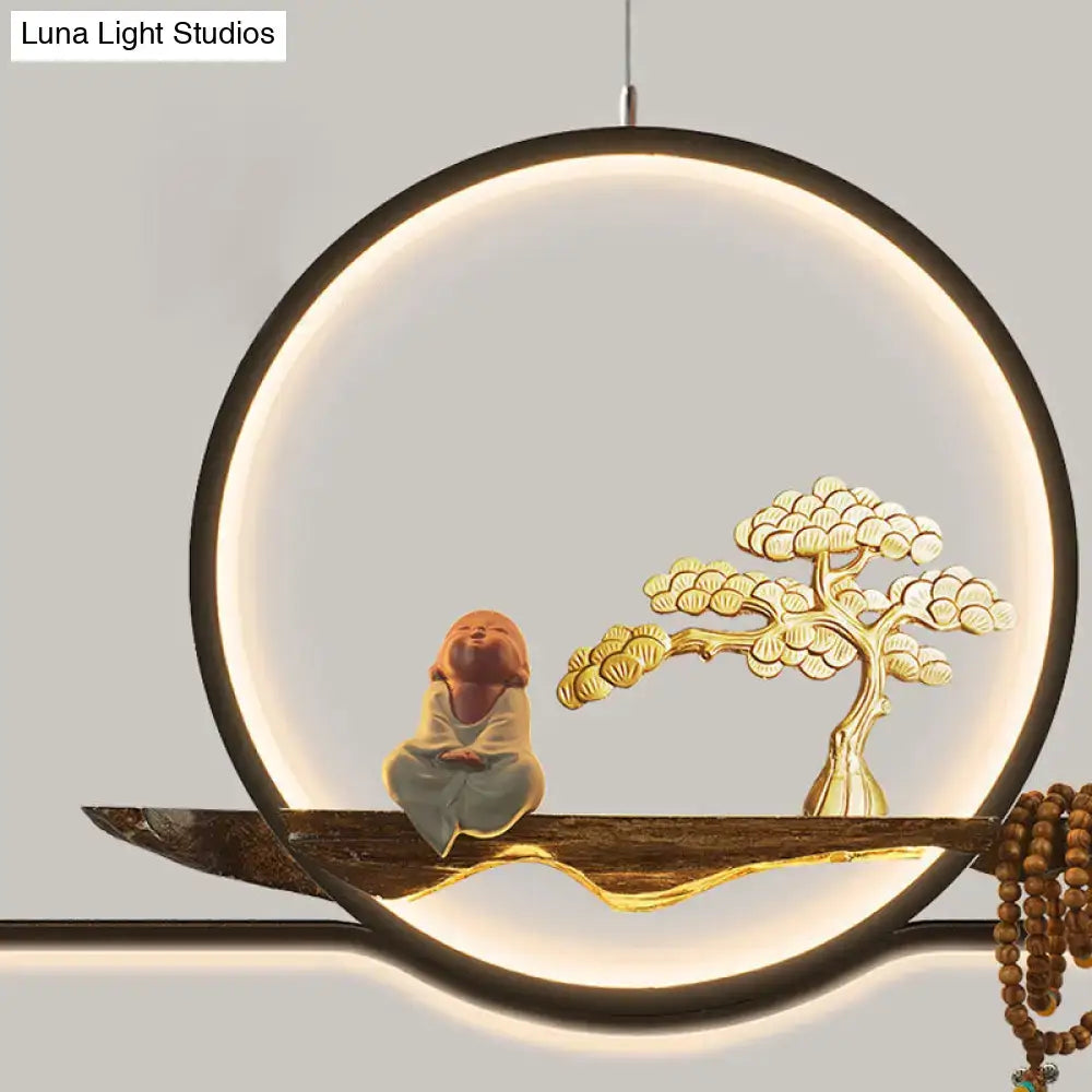 Minimalist gold linear hanging lamp with glowing circular pendant light, ceramic monk, and golden bonsai tree on wood branch