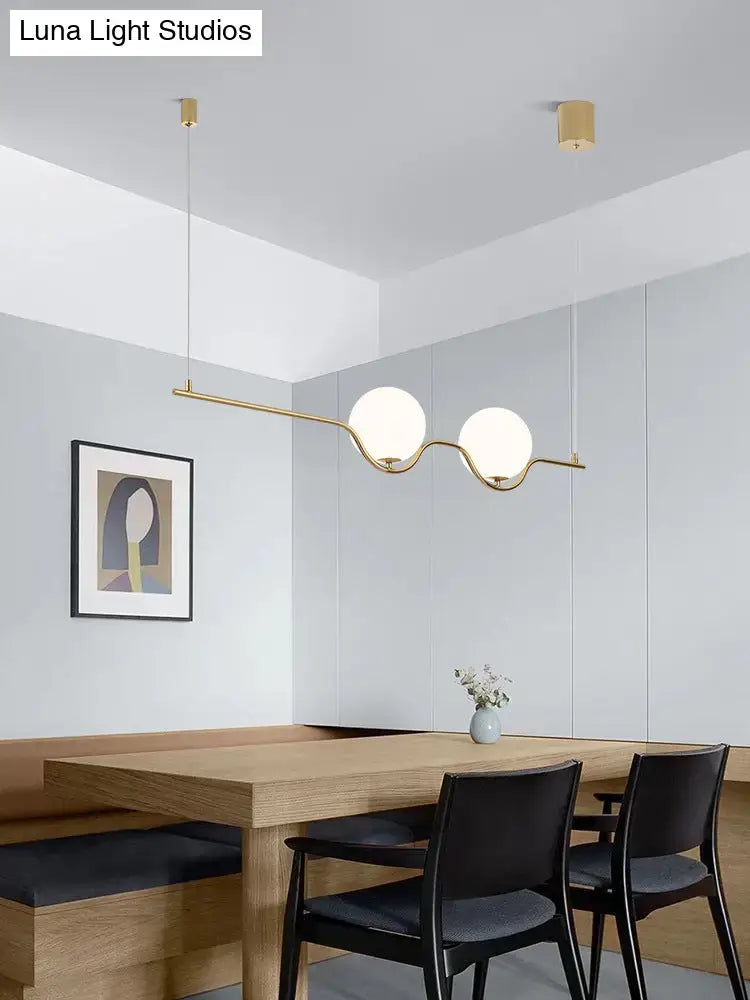 Minimalist gold metal island pendant ceiling light with two white glass spherical shades for dining table lighting