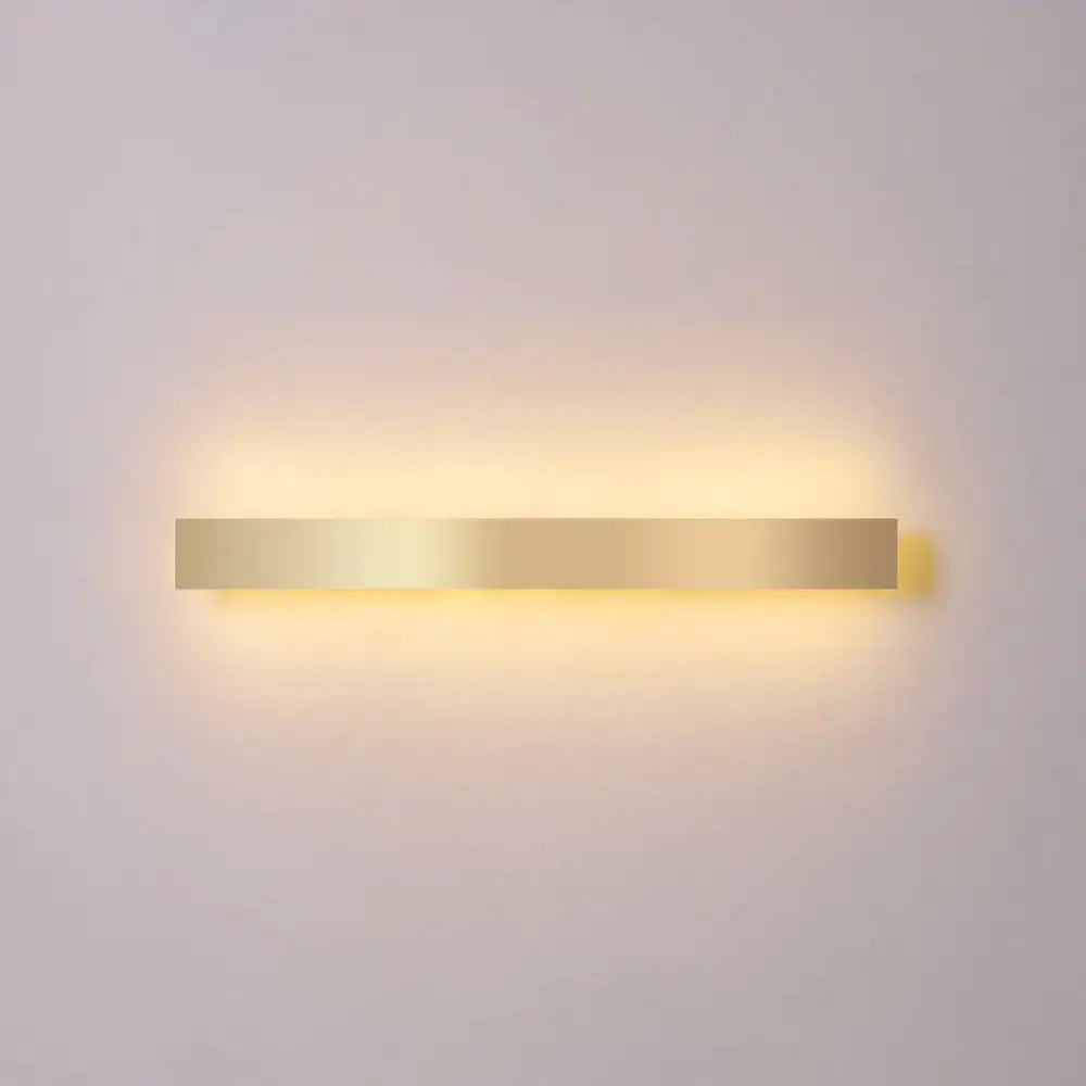 Minimalist gold plated rectangular wall sconce with led light emitting a warm soft glow for living room or bar use