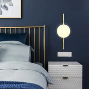 Minimalist gold wall light with frosted white globe shade and slender gold arm sconce light for bedroom use